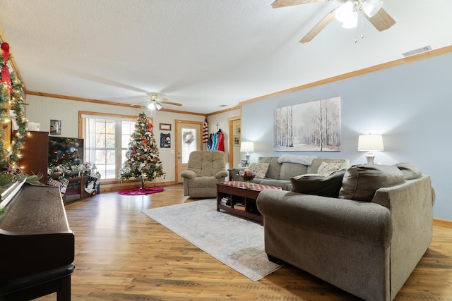 living room with crown molding, ceiling fan, a textured ceiling, and hardwood / wood-style flooring