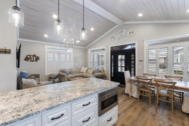 kitchen featuring white cabinetry, stainless steel microwave, pendant lighting, and wood-type flooring