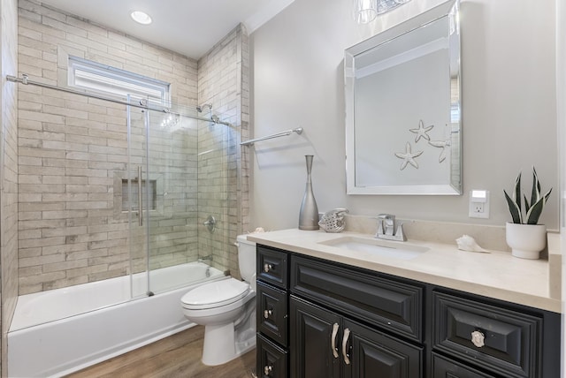 full bathroom featuring hardwood / wood-style flooring, vanity, toilet, and shower / bath combination with glass door