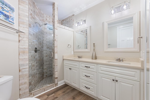 bathroom featuring hardwood / wood-style floors, vanity, a shower with shower door, and toilet