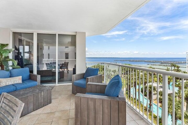 balcony featuring a view of the beach, an outdoor hangout area, and a water view