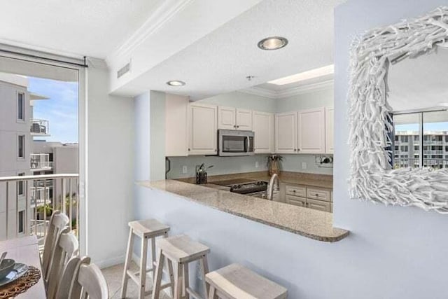 kitchen featuring kitchen peninsula, a wealth of natural light, ornamental molding, and appliances with stainless steel finishes