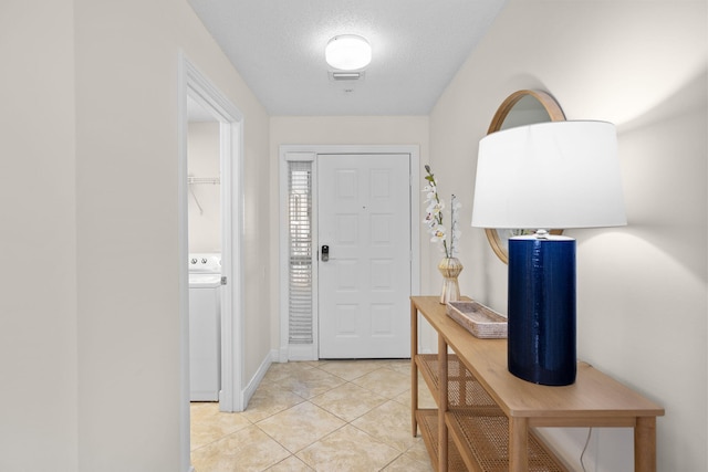 tiled entrance foyer featuring washer / clothes dryer and a textured ceiling