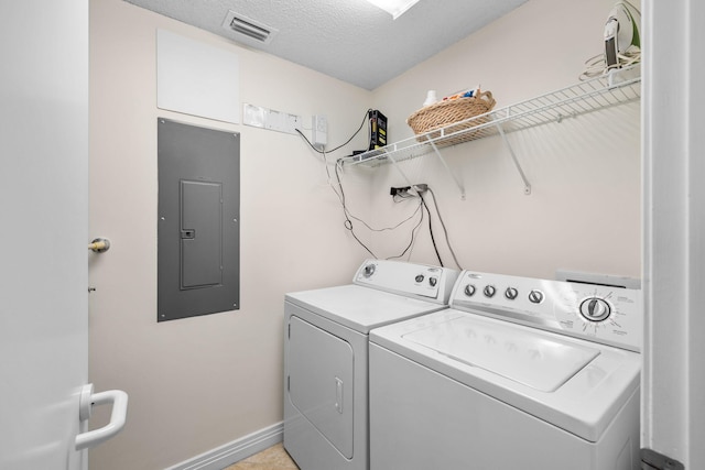 washroom featuring washing machine and clothes dryer, electric panel, and a textured ceiling