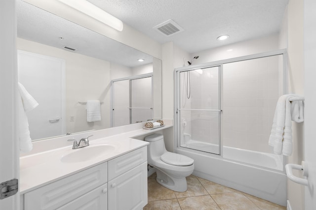 full bathroom with combined bath / shower with glass door, vanity, a textured ceiling, tile patterned flooring, and toilet