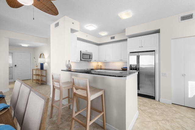 kitchen with ceiling fan, tasteful backsplash, white cabinetry, kitchen peninsula, and stainless steel appliances