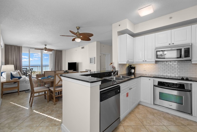 8501 Gulf Blvd Unit 3A, Navarre, FL 32566 - kitchen with stainless steel appliances, open floor plan, backsplash, a peninsula, and a textured ceiling