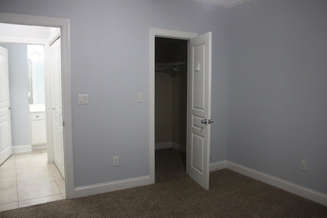 unfurnished bedroom featuring light colored carpet, a walk in closet, and a closet