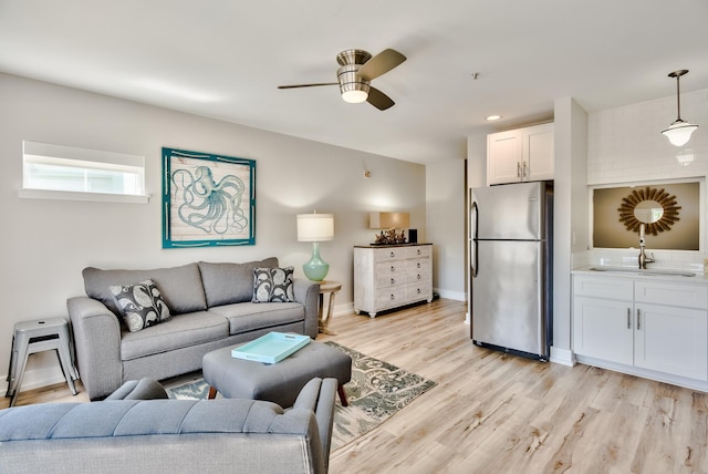 living room with ceiling fan, sink, and light hardwood / wood-style flooring