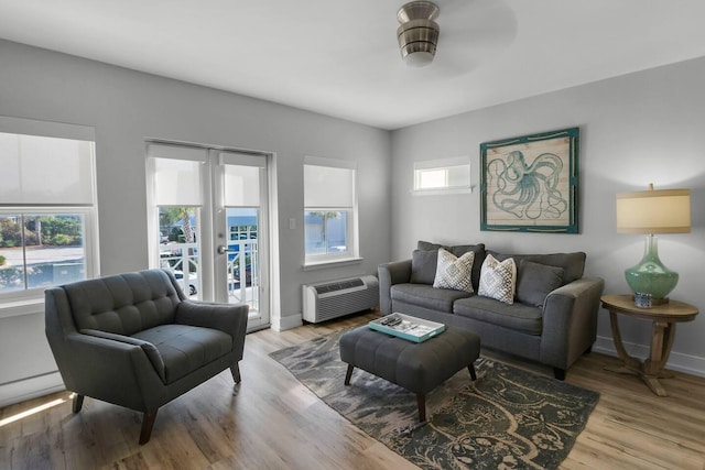 living room with ceiling fan, light wood-type flooring, and an AC wall unit