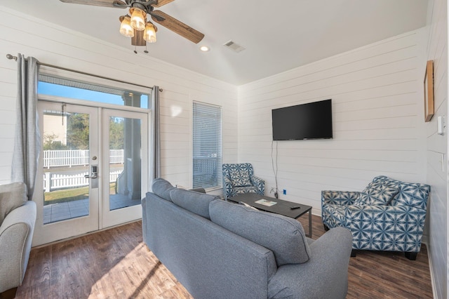 living room with ceiling fan, french doors, dark wood-type flooring, and wooden walls