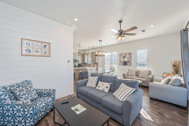 living room featuring ceiling fan and dark hardwood / wood-style flooring