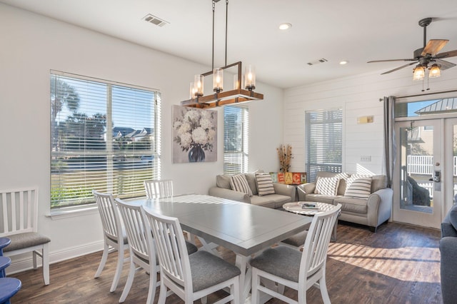 dining space with french doors, dark wood-type flooring, and ceiling fan with notable chandelier