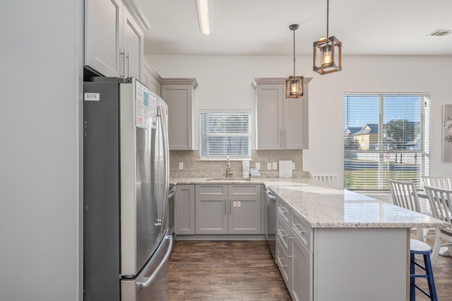 kitchen featuring a kitchen breakfast bar, sink, appliances with stainless steel finishes, tasteful backsplash, and kitchen peninsula