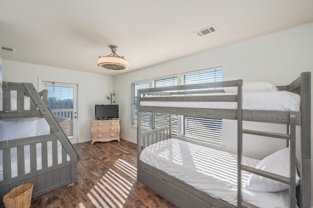 bedroom with multiple windows and dark wood-type flooring