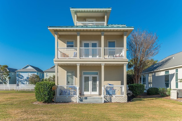 rear view of house with a lawn, a balcony, and covered porch