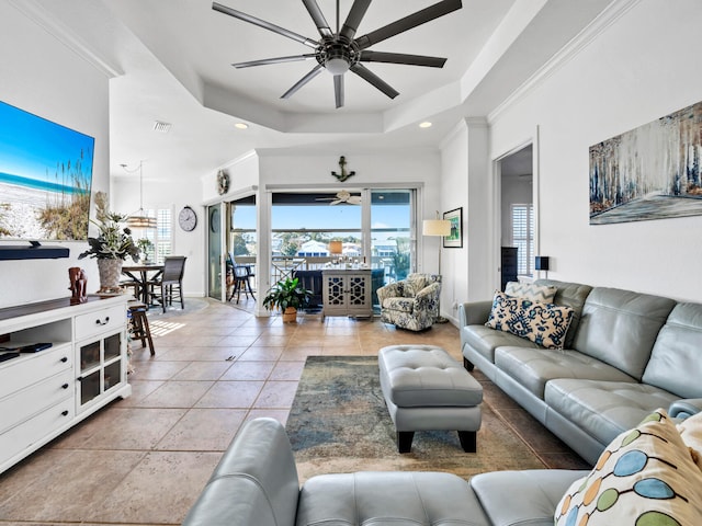 tiled living room with ceiling fan, a raised ceiling, and ornamental molding