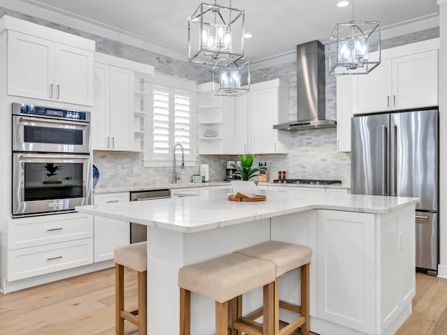 kitchen with white cabinetry, a center island, stainless steel appliances, and wall chimney range hood