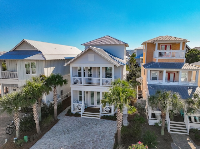 coastal home with covered porch, french doors, and a balcony