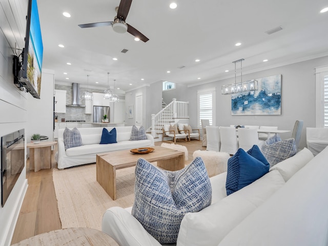 living room featuring ceiling fan, ornamental molding, and light hardwood / wood-style flooring