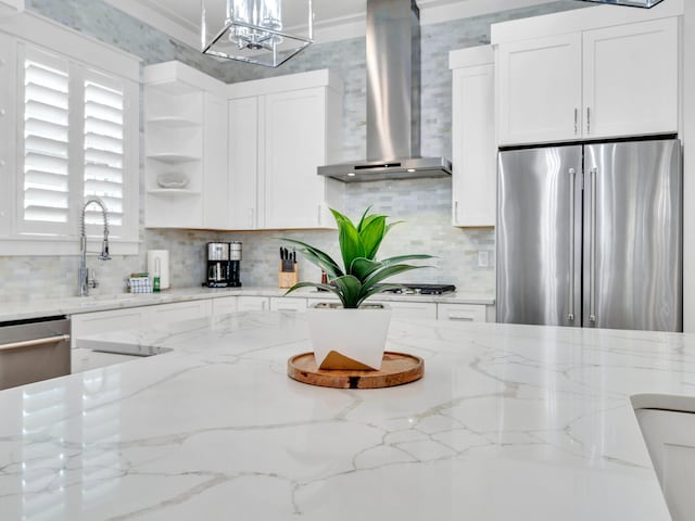 kitchen featuring white cabinetry, stainless steel refrigerator, light stone countertops, and wall chimney exhaust hood