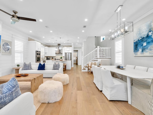 living room with light wood-type flooring, wooden walls, ceiling fan, and crown molding