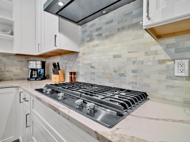 kitchen with tasteful backsplash, white cabinets, and stainless steel gas stovetop