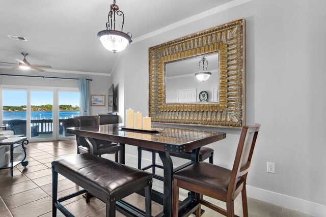 dining space with ceiling fan, tile patterned flooring, a water view, and ornamental molding