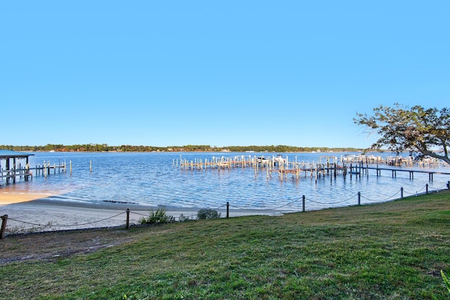 view of dock with a lawn and a water view