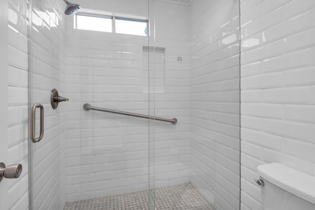 bathroom featuring toilet and a shower with door