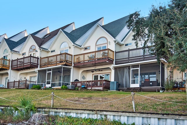 rear view of property with central air condition unit, a sunroom, a yard, and a balcony