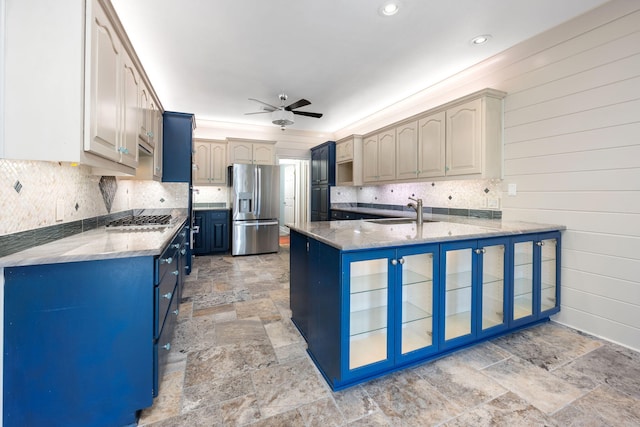 kitchen featuring a peninsula, a sink, stainless steel appliances, stone finish flooring, and blue cabinets