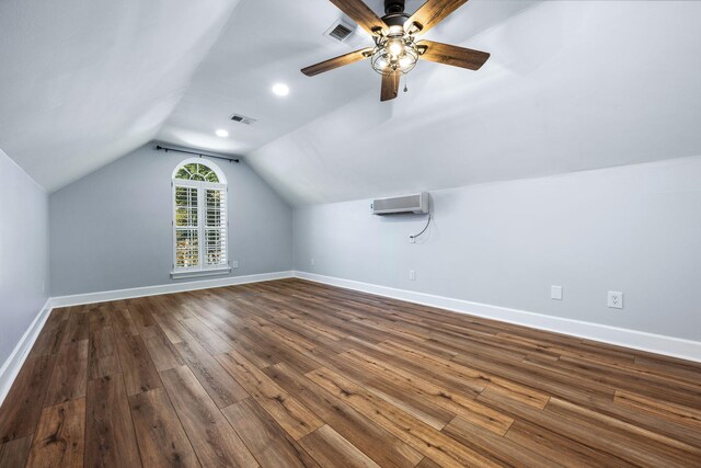 additional living space with dark wood-style floors, visible vents, baseboards, and a wall unit AC