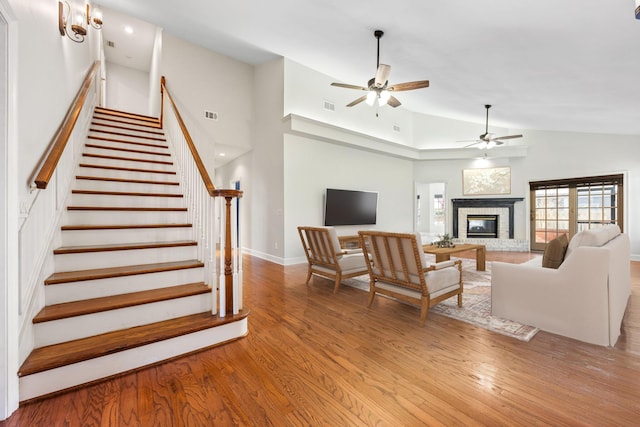 living area featuring visible vents, a ceiling fan, wood finished floors, a fireplace, and stairs