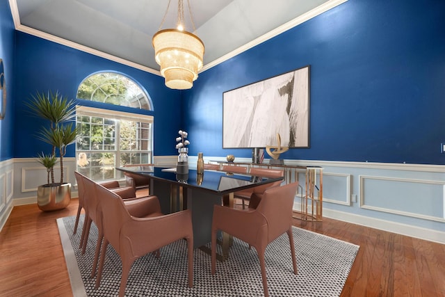 dining space featuring a wainscoted wall, crown molding, an inviting chandelier, and wood finished floors