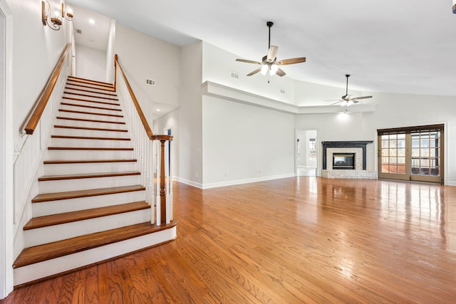 unfurnished living room with visible vents, a fireplace, stairs, and wood finished floors