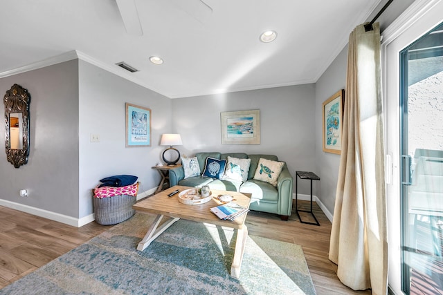 living room featuring a healthy amount of sunlight, light wood-type flooring, and crown molding