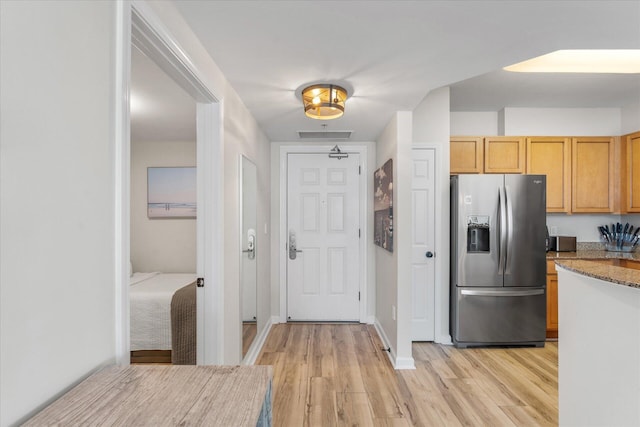 kitchen featuring stainless steel fridge, light hardwood / wood-style flooring, and light brown cabinets