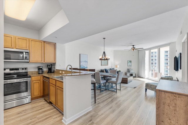 kitchen with ceiling fan with notable chandelier, sink, light hardwood / wood-style floors, kitchen peninsula, and stainless steel appliances