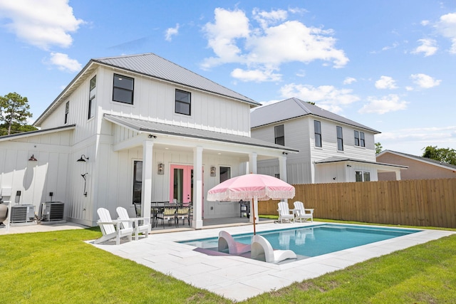 back of house featuring a fenced in pool, a yard, a patio, and central air condition unit