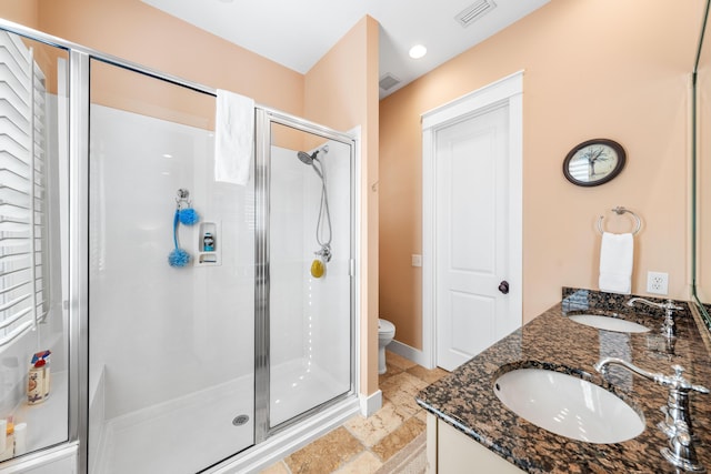 bathroom featuring vanity, toilet, and a shower with door