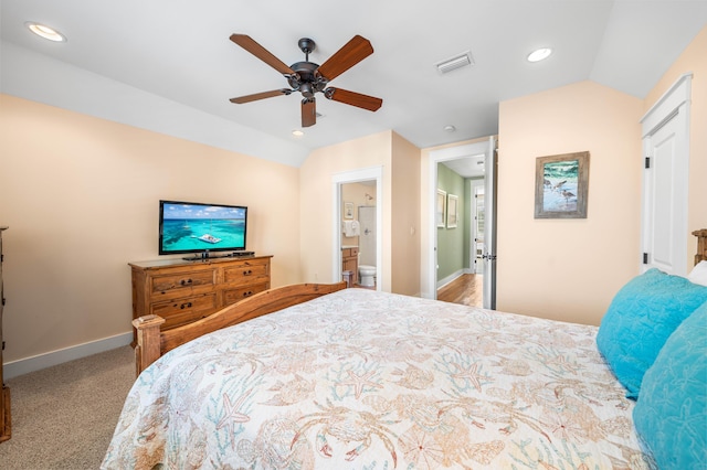 bedroom featuring light carpet, vaulted ceiling, ensuite bath, and ceiling fan