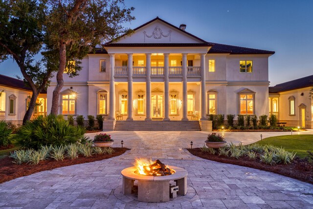 back house at dusk with a balcony and an outdoor fire pit