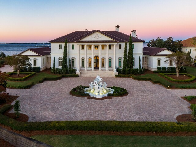 back house at dusk featuring a porch