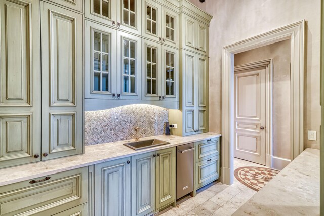 interior space with decorative backsplash, light stone countertops, sink, and cream cabinets