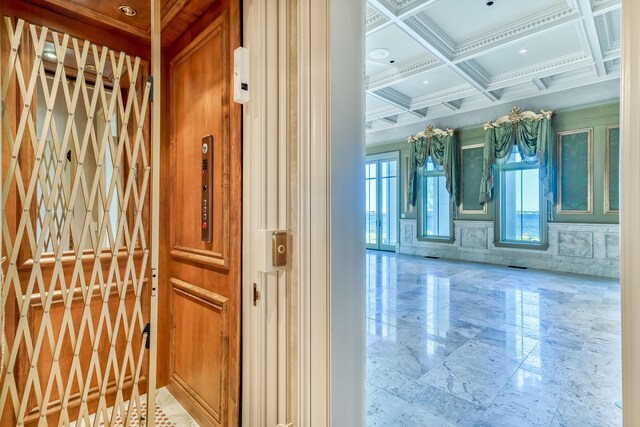 interior space with elevator, beamed ceiling, and coffered ceiling