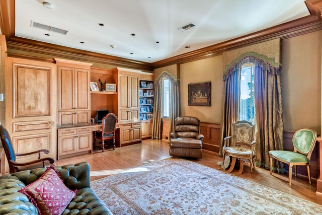 sitting room with built in desk, crown molding, and light hardwood / wood-style flooring