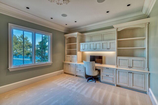 unfurnished office featuring light colored carpet, built in desk, and ornamental molding