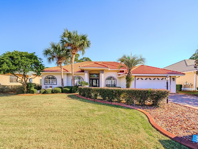 mediterranean / spanish-style house featuring a front yard and a garage