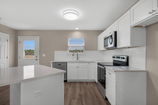 kitchen featuring backsplash, sink, hardwood / wood-style flooring, appliances with stainless steel finishes, and white cabinetry